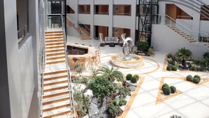 A spacious atrium with a central fountain, multiple staircases, and a variety of indoor plants. - Tio Sea Resort (Al Khor)