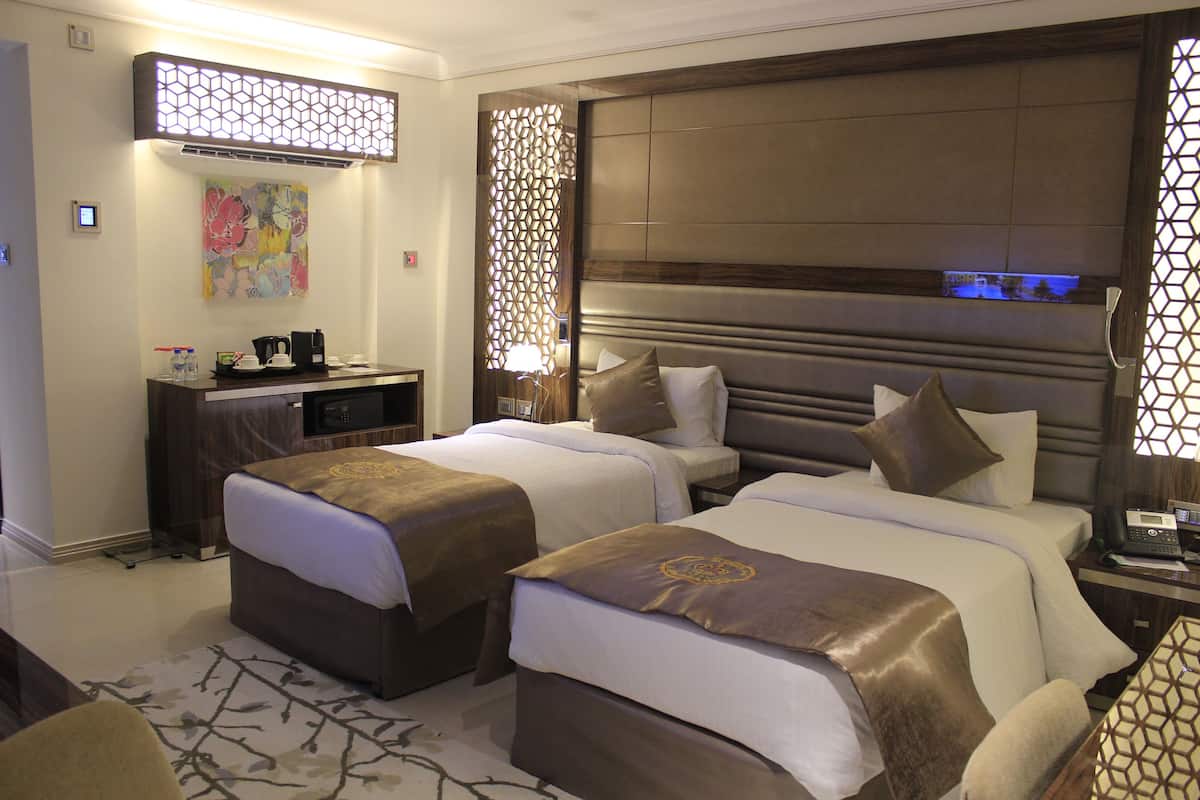 Une chambre d’hôtel avec deux lits, un bureau et un panneau décoratif au mur.