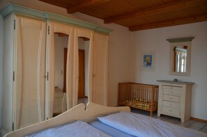 Ein Schlafzimmer mit einem Bett, einem Holzschrank, einem Babybett und einer Kommode.