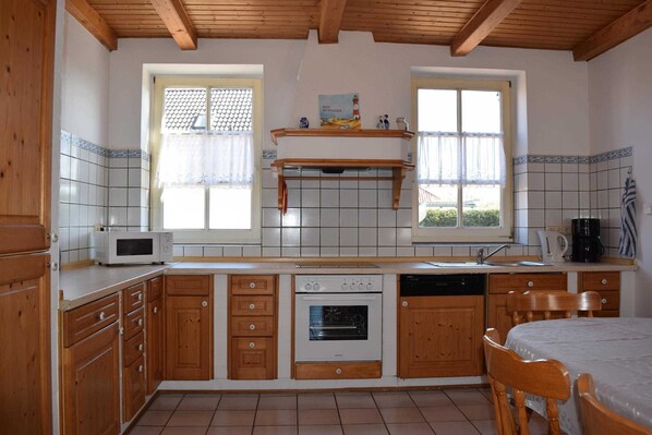 Une cuisine avec des meubles de rangement en bois, un four à micro-ondes, un four traditionnel, un évier et une fenêtre donnant sur un beau paysage.