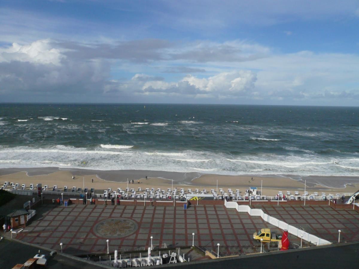Une vue sur la plage avec une zone pavée, un véhicule jaune et l’océan en arrière-plan.