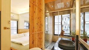 Ett modernt hotellrum med en vägg av trä, en säng, ett badrum med en stor spegel och utsikt över staden.