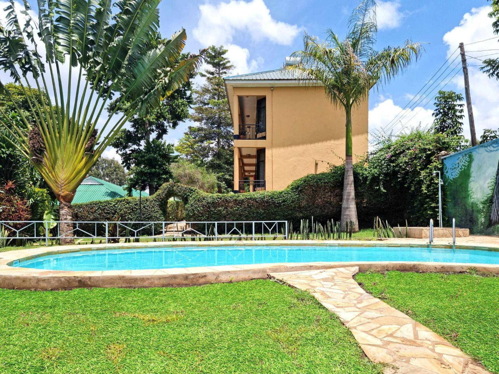 A swimming pool with a stone pathway leading to a building with a balcony.