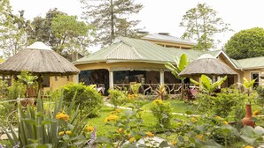 A traditional house with a thatched roof, surrounded by lush greenery and a well-maintained garden.