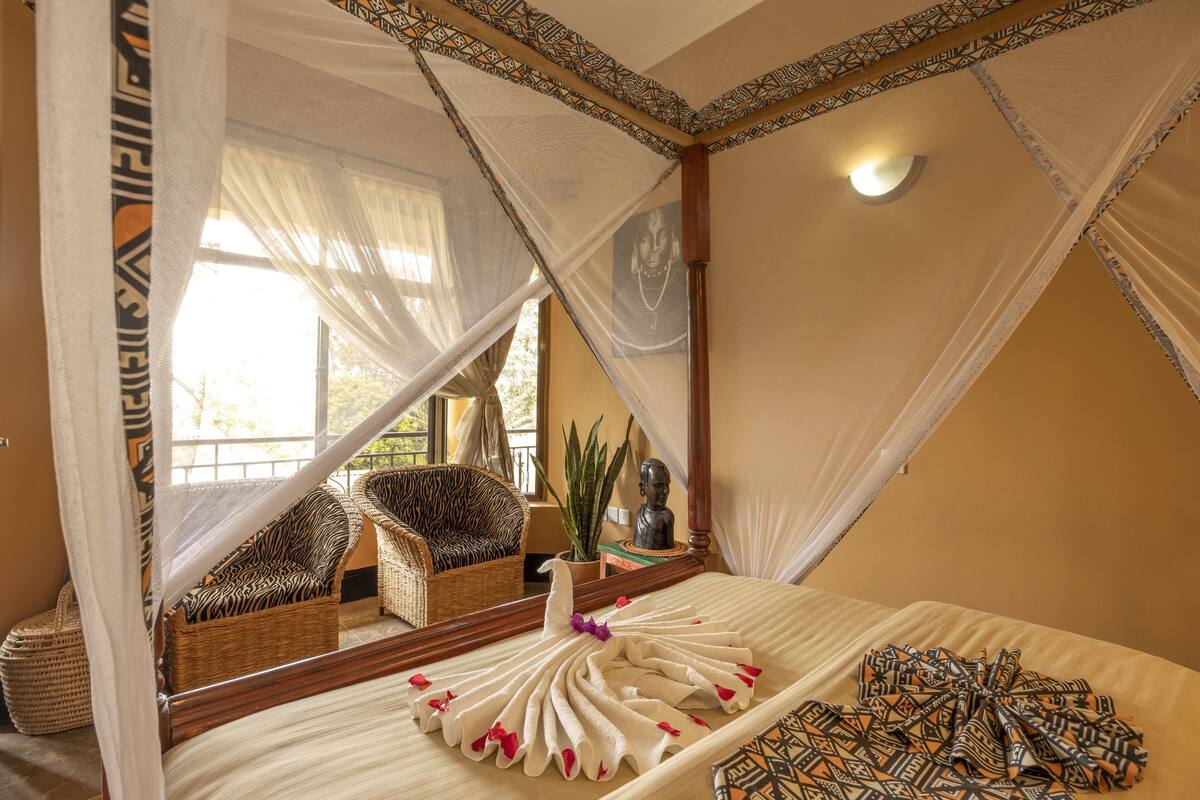 Una habitación con una cama, una silla de mimbre, una planta en maceta y un espejo.