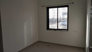 Ein Zimmer mit großem Fenster, weißen Wänden und einer sichtbaren Steckdose.