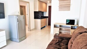 A modern kitchen with a refrigerator, microwave, and wooden cabinets.