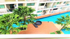 A pool area with palm trees and a lounge chair. - Laguna Beach Resort 1 Jomtien (Pattaya)