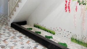 Eine Treppe mit weißer Geländer, einem gemusterten Boden und einer Wand mit roten, hängenden Blüten und einem Wandgemälde.