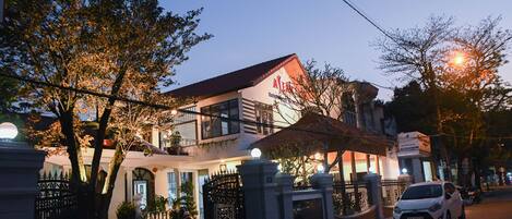 Hotel entrance with a traditional architectural style and a balcony above.
