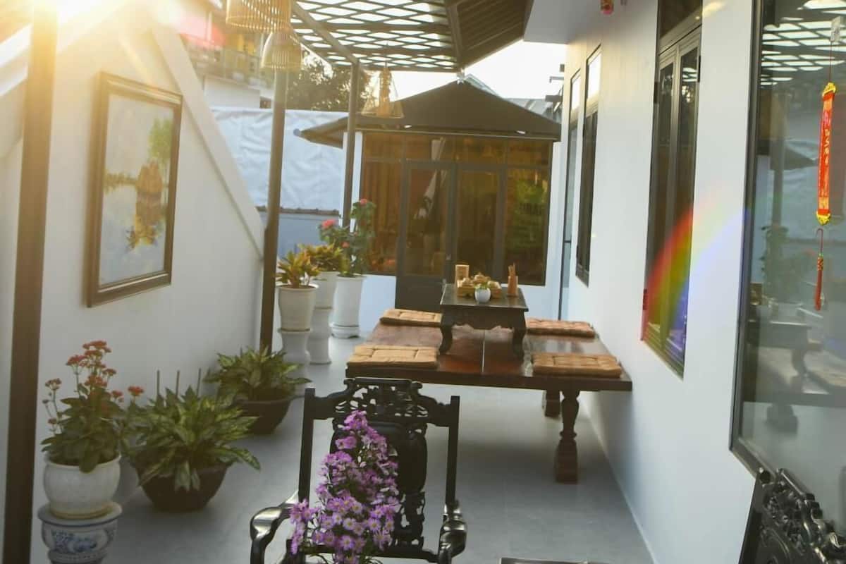 A sunlit patio with a table, chairs, potted plants, and a decorative lantern.
