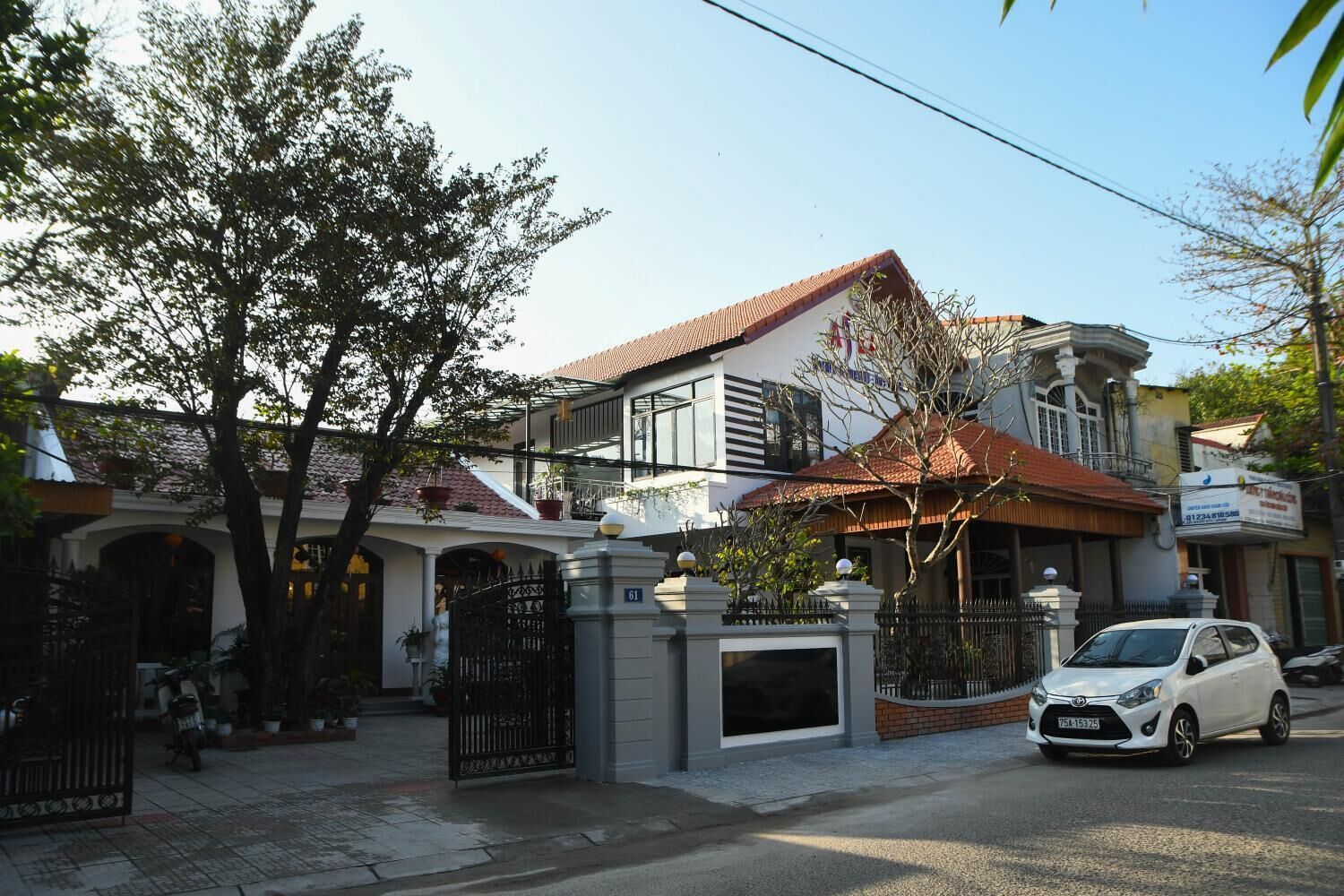 A two-story house with a tiled roof, a gated entrance, and a parked white car.