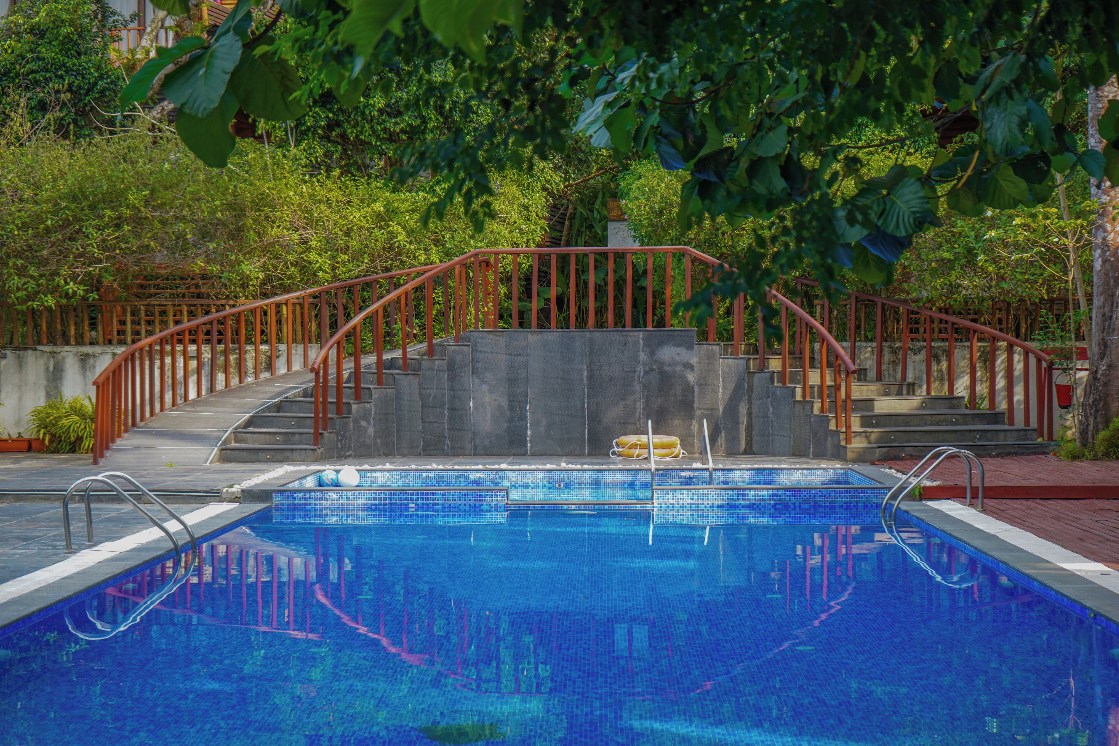 Una piscina con una escalera metálica roja que lleva a una plataforma de hormigón.