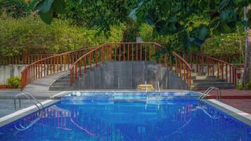 A swimming pool with a red metal staircase leading up to a concrete platform.
