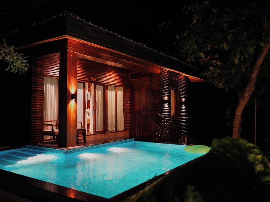Una casa de madera con piscina por la noche.