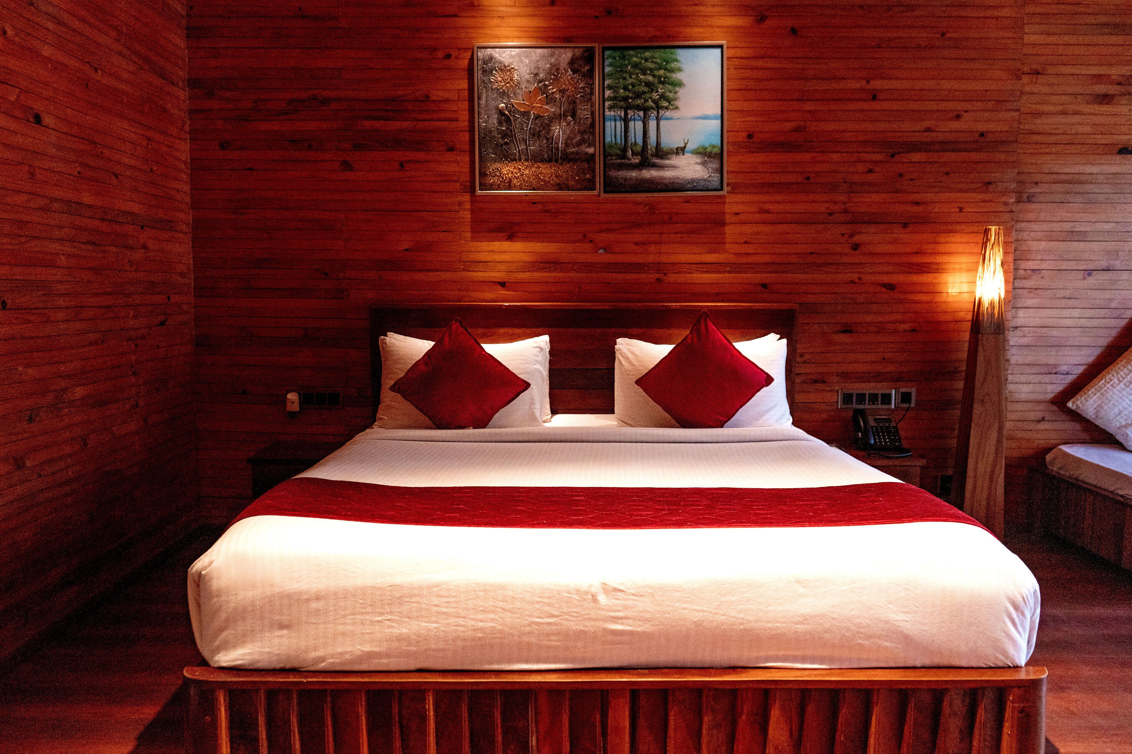 A wooden room with a bed, a nightstand, and a wall-mounted phone.