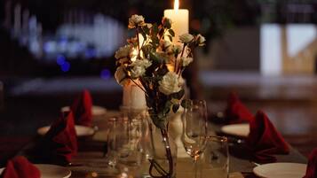 Mesa lista para cenar con una vela y un jarrón de flores.