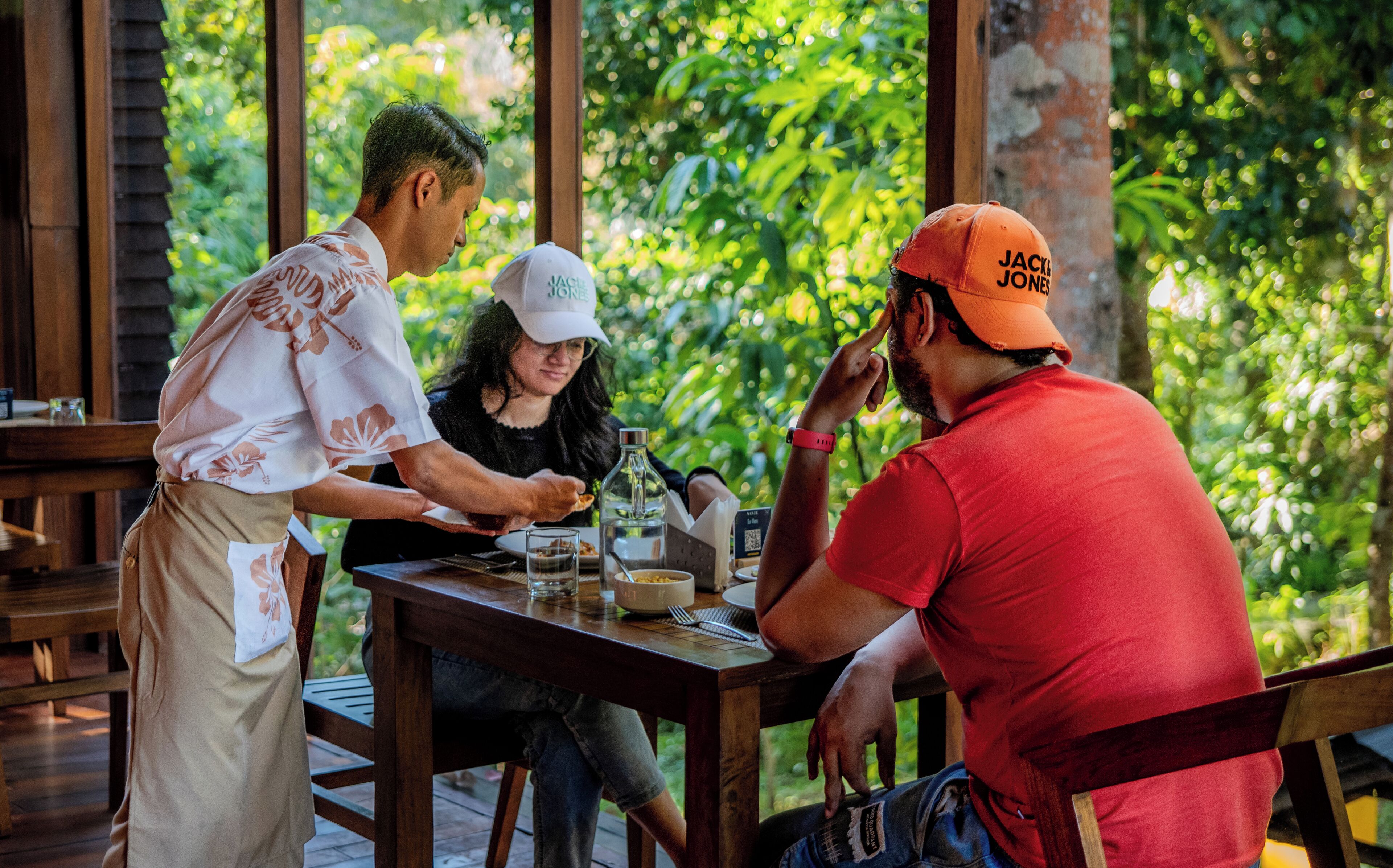 Una terraza de madera con una mesa lista para comer, rodeada de abundante vegetación.