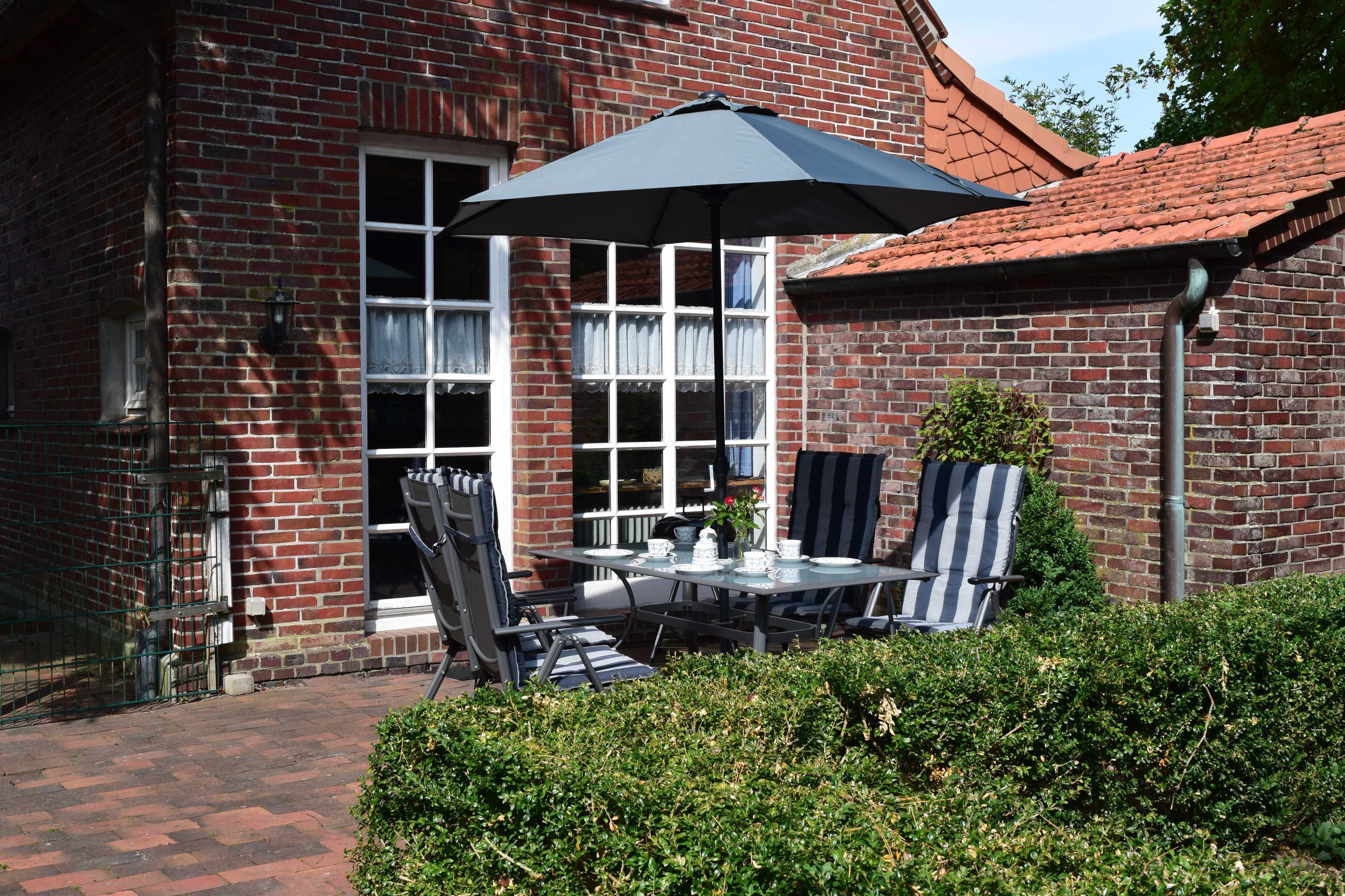A brick building with a patio area featuring a table, chairs, and an umbrella.