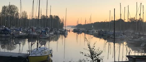 A marina with boats docked, calm water, and a clear sky.