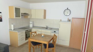 Una cucina funzionale con un tavolo da pranzo, sedie, lavandino, piano cottura e un orologio appeso al muro.