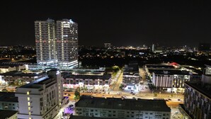 Een nachtelijk stadsbeeld met moderne gebouwen, een drukke kruising en zichtbare straatverlichting.
