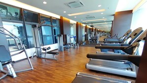 Een fitnessruimte met loopbanden, krachttoestellen en een spiegelwand.