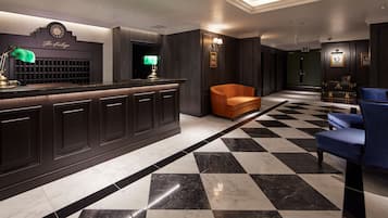 A lobby with a checkered floor, a reception desk, and seating areas.