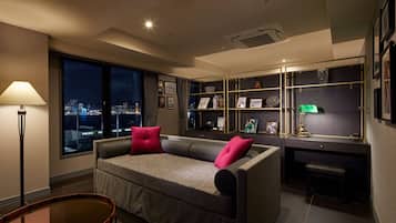 A modern living room with a sofa, a desk, and a bookshelf.