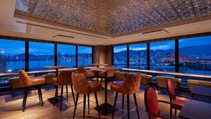 A modern dining area with a city view, large windows, and a high ceiling with intricate patterns. - Centurion Hotel & Spa Vintage Kobe (Kobe)