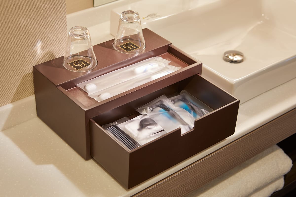 A bathroom with a brown toiletry box containing a bottle, a toothbrush, and a razor.