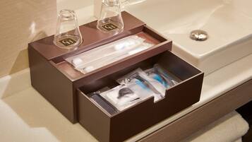 Un baño con un neceser marrón que contiene una botella, un cepillo de dientes y un afeítador.