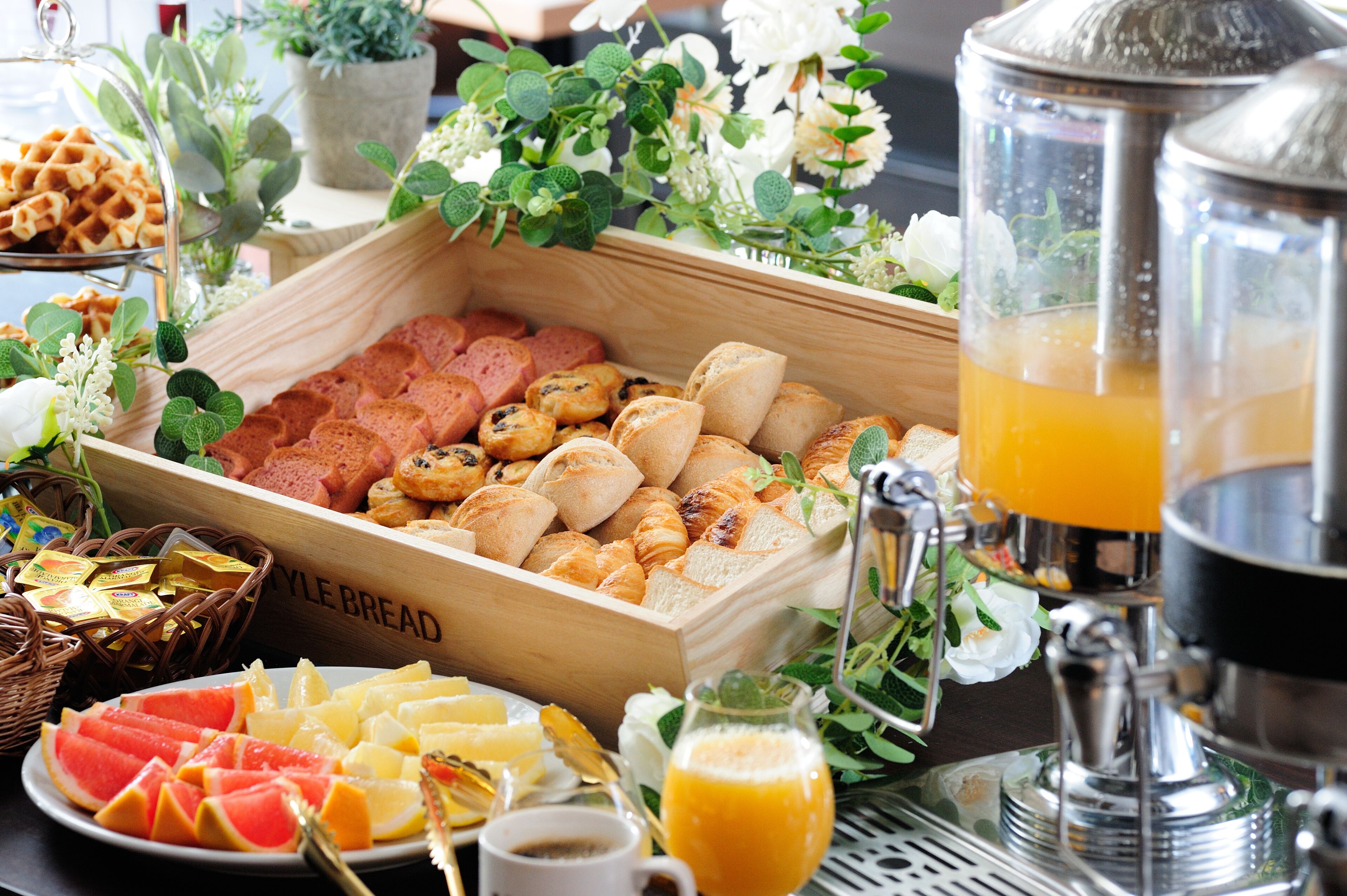 Un bufé de desayuno con diversos pasteles, pan y fruta.