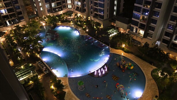 A large indoor swimming pool surrounded by palm trees and a children's play area.