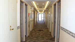 Un pasillo de hotel con alfombra estampada, paredes blancas y puertas a ambos lados.