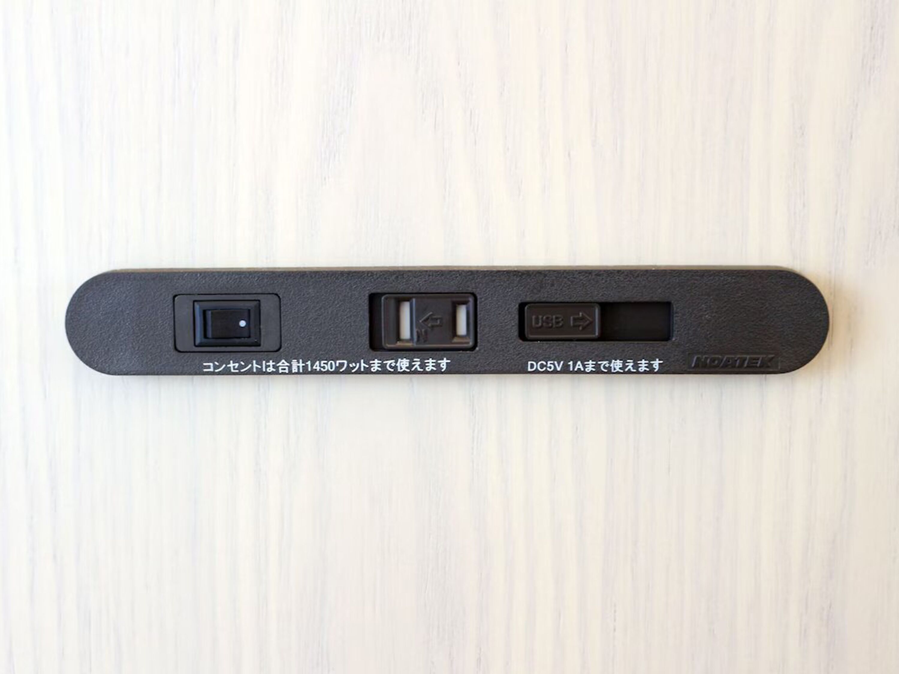 Una regleta negra con tres puertos USB y un puerto DC5V 1A, etiquetada con texto en japonés.
