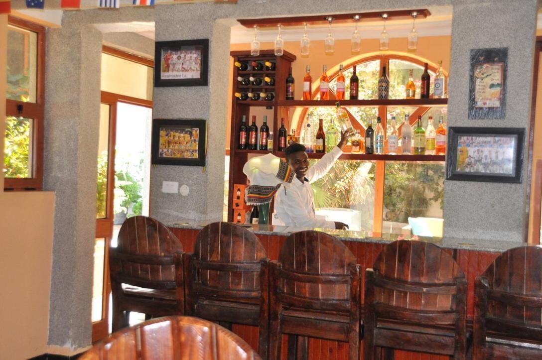Un coin bar avec des chaises en bois et une étagère remplie de bouteilles.