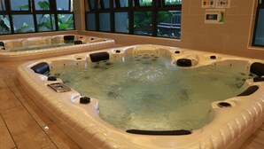 Un jacuzzi interior amplio con varias zonas de estar y un panel de control.