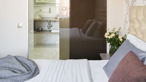 A modern bedroom with a bed, a nightstand, a lamp, and a view into the bathroom. - Friendly Hotel (Kyiv)