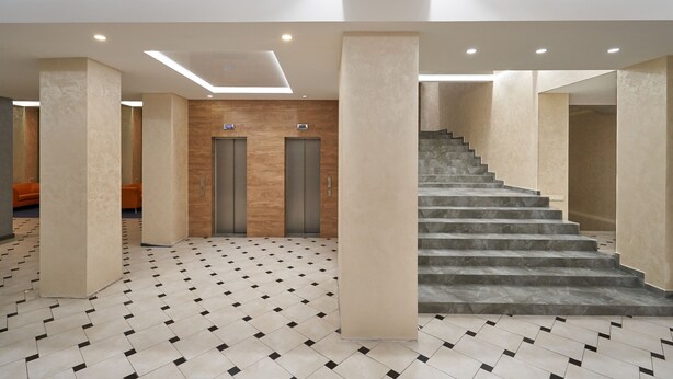 A modern hotel lobby with a geometric patterned floor, two elevators, and a staircase. - Friendly Hotel (Kyiv)