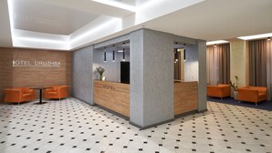 A hotel reception area with a reception desk, two orange chairs, and a patterned floor. - Friendly Hotel (Kyiv)
