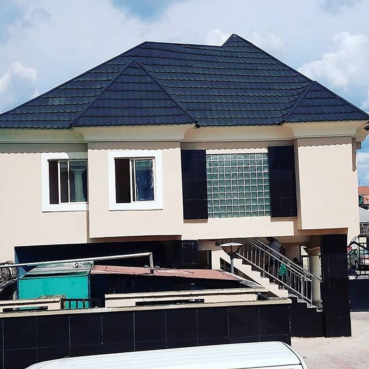 Una casa a due piani con tetto scuro, un balcone e una scalinata che conduce al piano superiore.