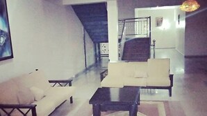 A spacious living room with a sofa, armchair, and coffee table. A staircase is visible in the background leading to an upper floor. - Davok Suites Uyo (Uyo)