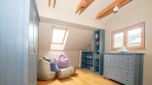 A room with a wooden floor, a blue wardrobe, a blue dresser, a window, and a skylight.