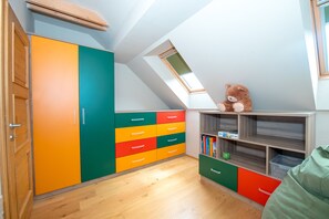 A room with a sloped ceiling, a skylight, a wooden door, and a colorful cabinet with drawers. - Bovecation House (Bovec)