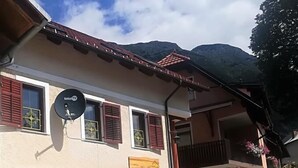 A two-story building with red shutters, a satellite dish, and a balcony.