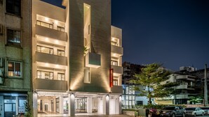 A modern hotel with a prominent vertical structure, multiple balconies, and a well-lit entrance. - Hotel Si (Taichung)