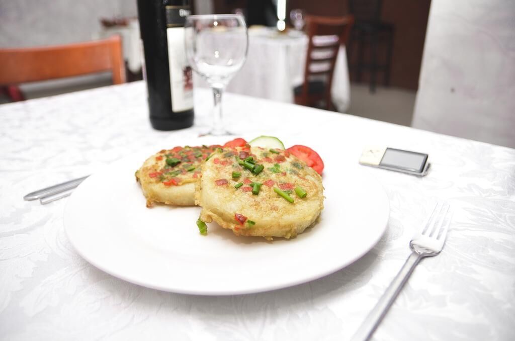 Une assiette de nourriture sur une table, avec un verre à vin et une bouteille en arrière-plan.