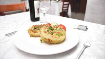 Une assiette de nourriture sur une table, avec un verre à vin et une bouteille en arrière-plan.