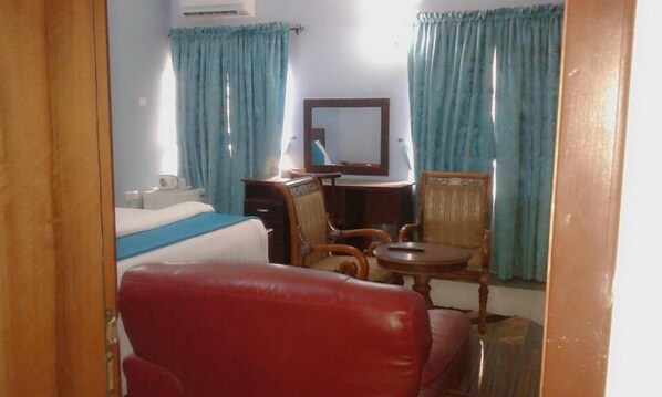 A hotel room with a bed, a desk, a chair, and a small table.
